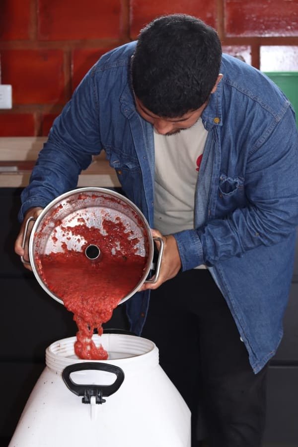 Edinson Argote adding real fruit pulp to a co-fermentation tank at Finca Quebraditas